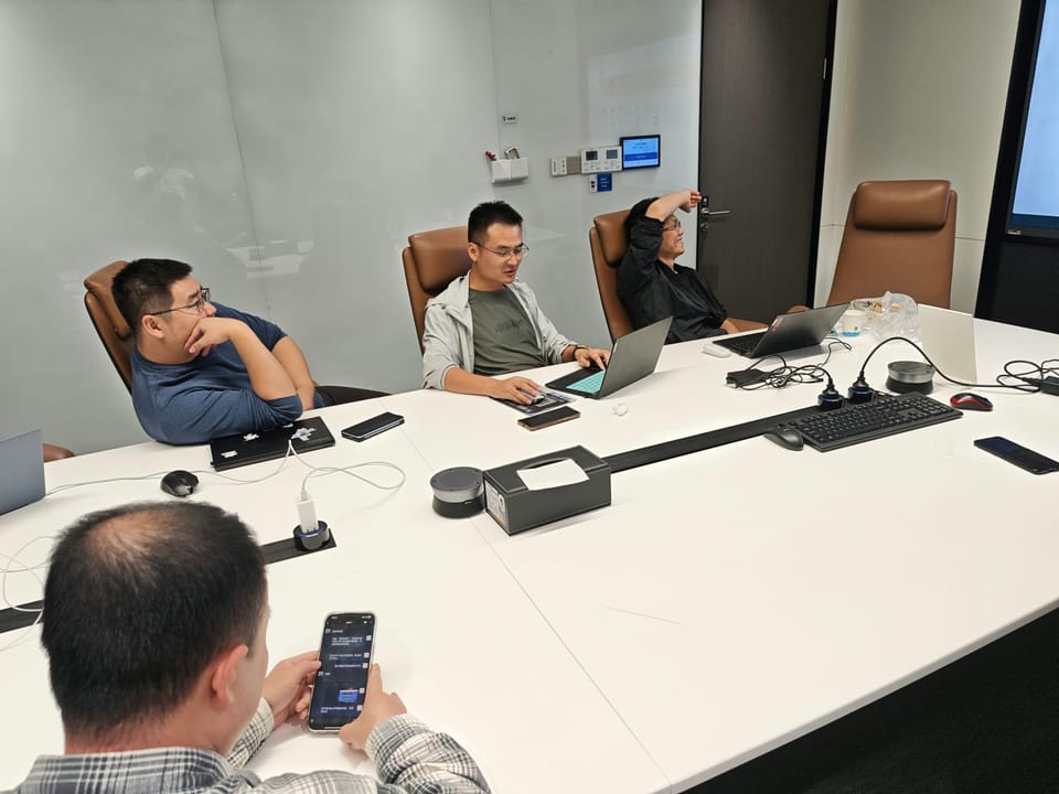 Four people in a meeting room with laptops
