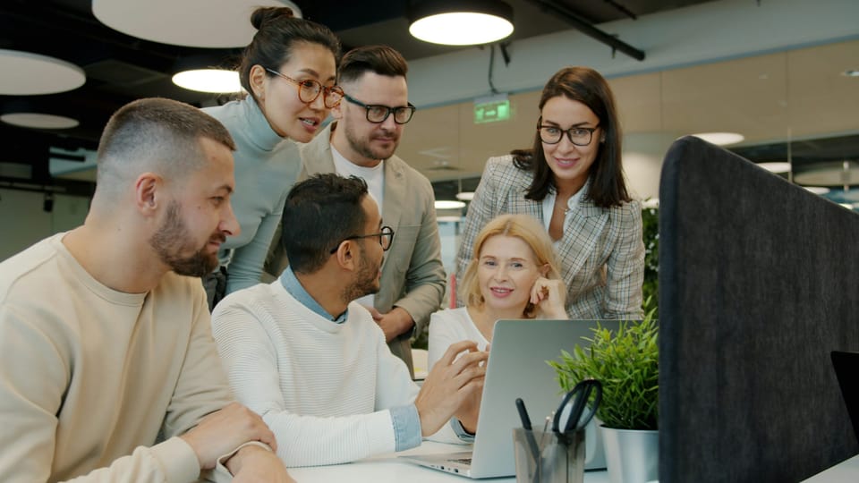 Diverse team collaborating around a laptop in an office